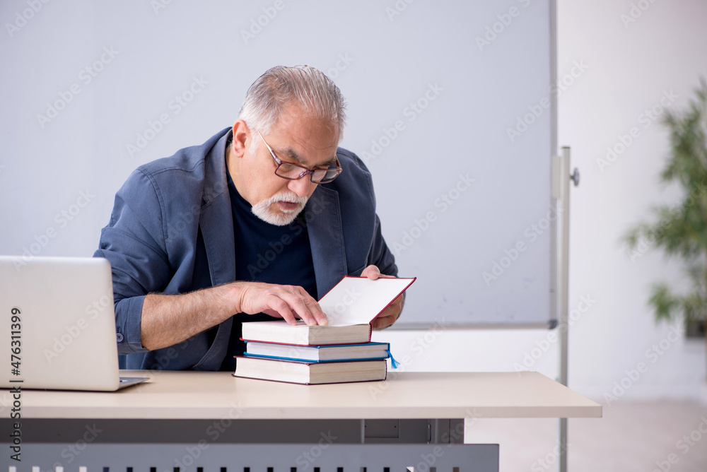 Old male teacher in the classroom Old male teacher in the classroom