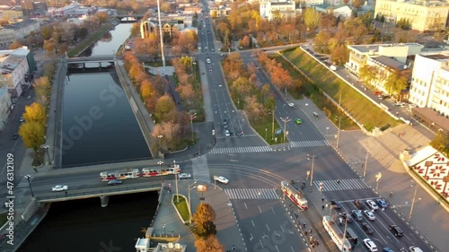 Flagpole with flag of Ukraine with epic sunny autumn cityscape, city streets with transport traffic, aerial view above river Lopan embankment near Svyato-Pokrovskyy Monastyr in Kharkiv, Ukraine photo
