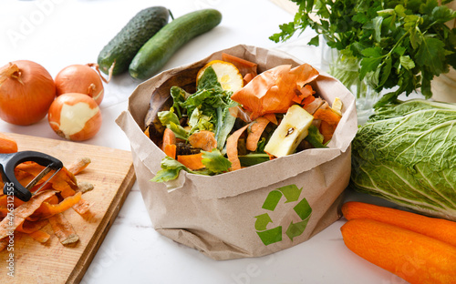 Sorted kitchen waste in paper eco bag on kitchen counter top. Compost-container. Sustainable life style. Vegetable and fruit peels, scraps from food preparation collected in trash-pack for recycling