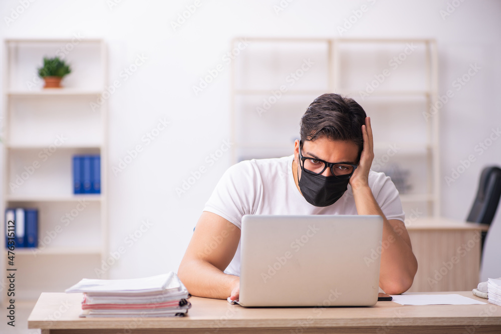 Young male student employee working at workplace during pandemic