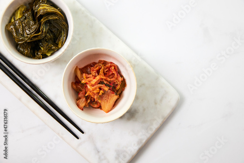 Top view of kimchi and fermented bok choy served in two white bowls