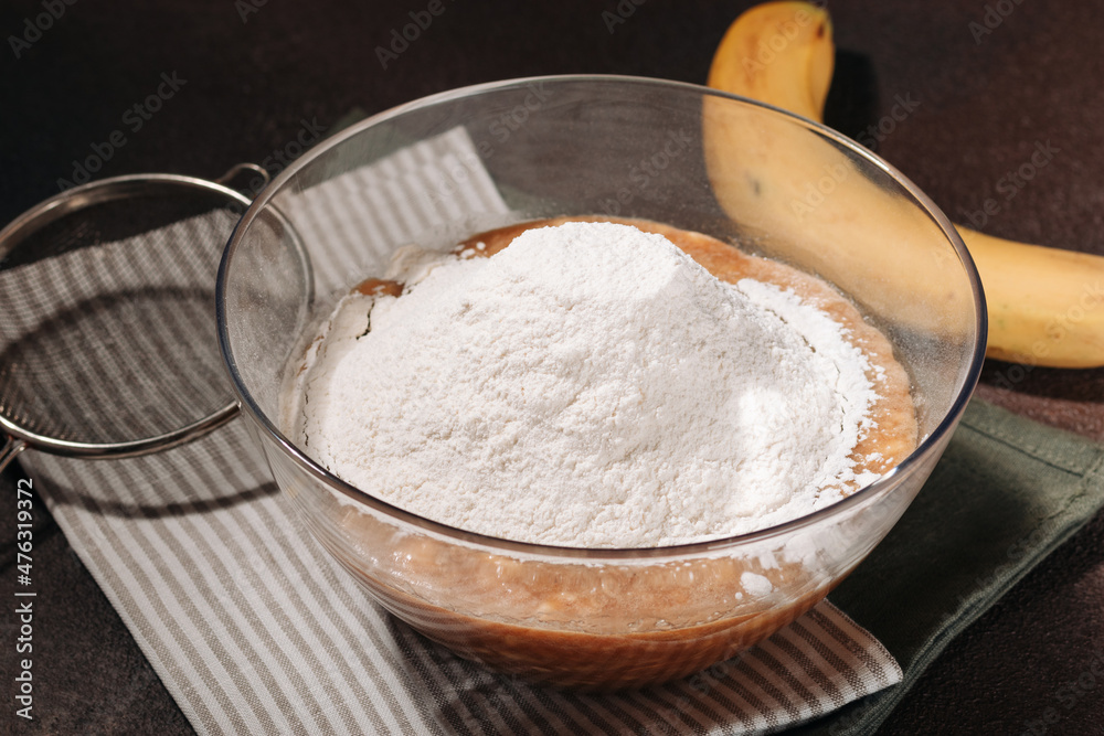 Banana bread mix and sifted flour in transparent bowl on brown background Banana bread mix and sifted flour in transparent bowl on brown background