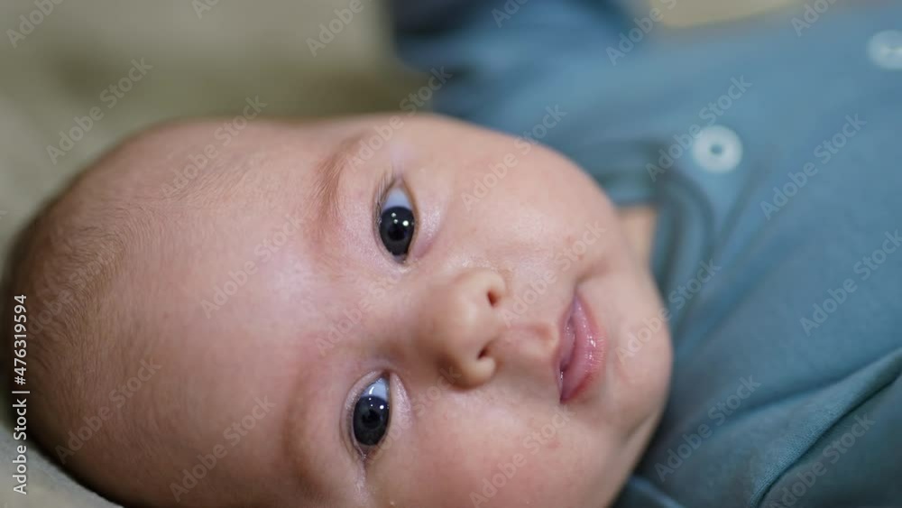 Adorable baby face looking in camera. Grey-eyed baby lying with his head facing camera. Close up. Adorable baby face looking in camera. Grey-eyed baby lying with his head facing camera. Close up.