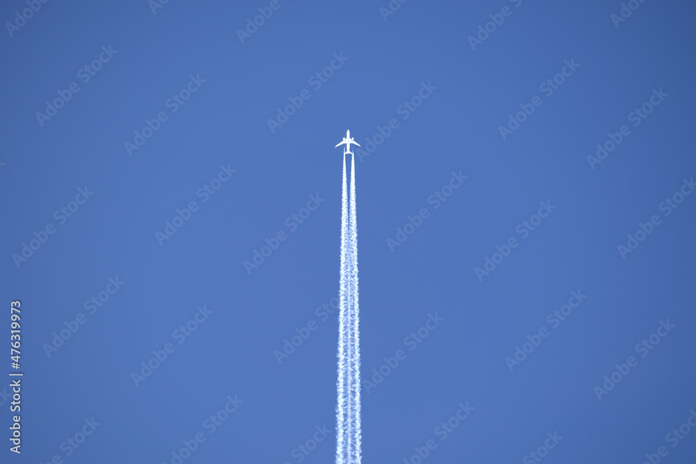 Distant passenger jet plane flying on high altitude on clear blue sky leaving white smoke trace of contrail behind. Air transportation concept Distant passenger jet plane flying on high altitude on clear blue sky leaving white smoke trace of contrail behind. Air transportation concept