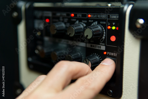 Close up of a man's hand switching on an amplifier.