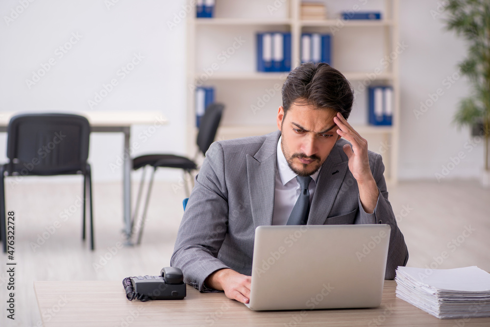 Young male employee and too much work in the office Young male employee and too much work in the office
