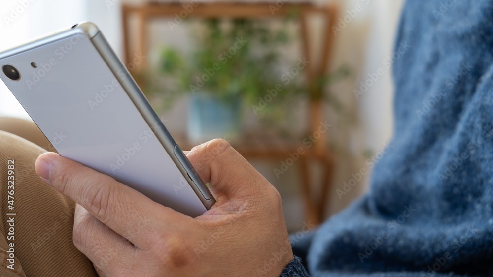 部屋で携帯電話の操作をする男性。 部屋で携帯電話の操作をする男性。