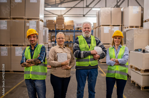 Group portrait of staff at distribution warehouse. Warehouse team standing with arms crossed in factory.