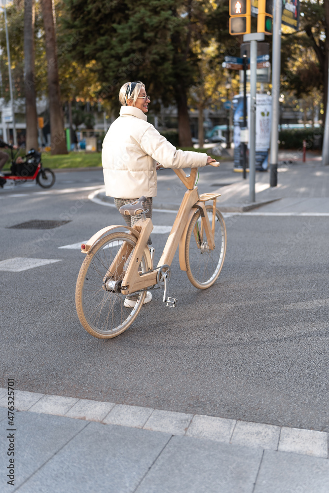 Positive woman with wooden eco bike crossing street
