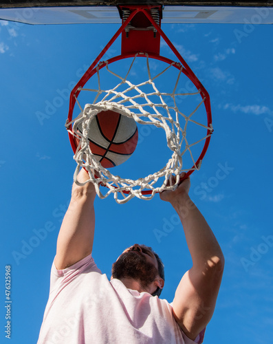 basketball player throws the ball into the hoop outdoors, male basketball