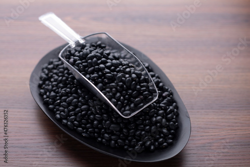 black bean on wood table and plastic spoon. Protein nutrition ingredient for vegetarian.