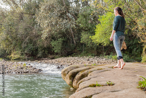 Woman walking on rocks barefooted with her shoes in hands