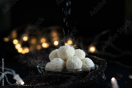 Coconut balls, typical czech christmas candy, still life with homemade confectionery with lights in the background, raw, easy, vegan, woman hand photo