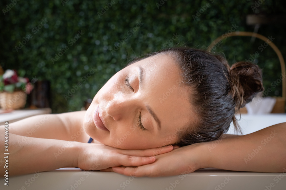 Obraz premium Relaxed Woman resting head in hands in hot tub