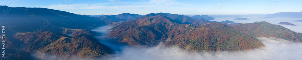 Autumn mountain landscape panorama. Peaks above the fog. Drone view.