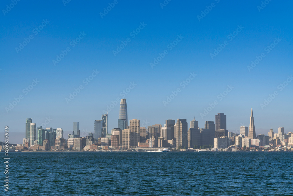 Naklejka premium A picturesque skyline of San Francisco Panorama at sunrise from Treasure Island, California, United States. Panoramic view of cityscape with mist and foggy air at morning day time.