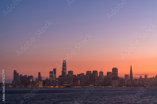 A picturesque skyline of San Francisco Panorama at sunset golden hour from Treasure Island, California, United States. Panoramic view of cityscape with mist and foggy air. Illuminated dusk city © VideoFlow