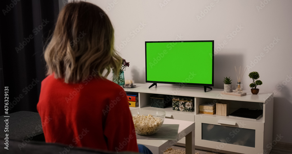 Woman watching TV focused eating popcorn. Green Screen TV Chroma Key. Movie time Sports Match, News, Sitcom TV Show in the evening. Woman watching TV focused eating popcorn. Green Screen TV Chroma Key. Movie time Sports Match, News, Sitcom TV Show in the evening.