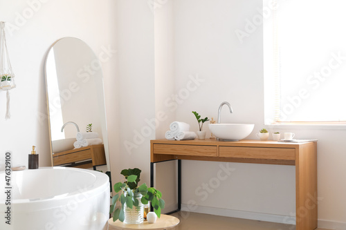 Interior of light bathroom with mirror and table
