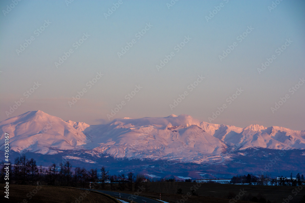 Fototapeta premium 夕日を反射して輝く雪山 十勝岳