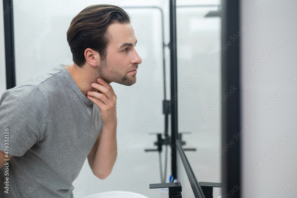 Man near the mirror scrutinizing himself Man near the mirror scrutinizing himself