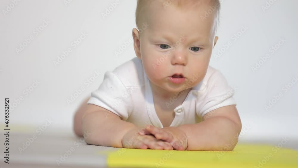 Portrait of the caucasian fair-haired baby boy who begins to learn to crawl on the floor Portrait of the caucasian fair-haired baby boy who begins to learn to crawl on the floor