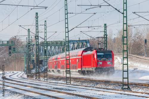 Red train runs on the tracks covered by snow