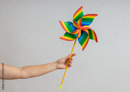 Rainbow weather vane in a female hand on a white background, close up, LGBT concept