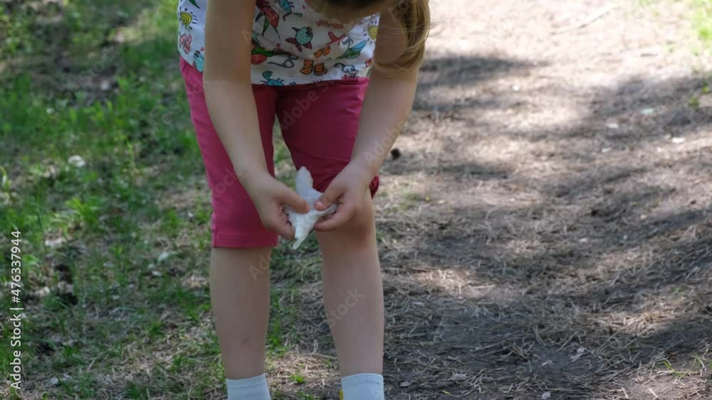 Child cleaning knees with wet napkin after fall Child cleaning knees with wet napkin after fall