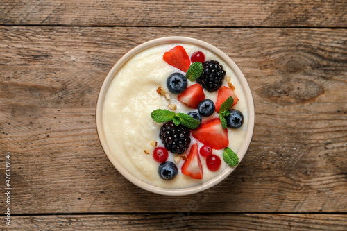 Delicious semolina pudding with berries on wooden table, top view photo