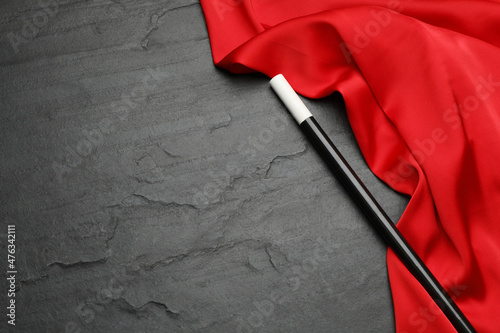 Fotografia Beautiful magic wand and red fabric on black table, top view