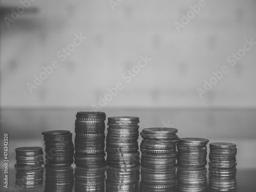 Close up shot of stacked coins that starts from a few to lot of coins that look like graph or pyramid. Edited with black and white tone