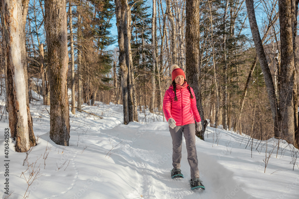 Winter snowshoe hiking people. Snowshoeing asian multiracial woman in winter forest on hike in snow wearing snowshoes living healthy active outdoor lifestyle Winter snowshoe hiking people. Snowshoeing asian multiracial woman in winter forest on hike in snow wearing snowshoes living healthy active outdoor lifestyle