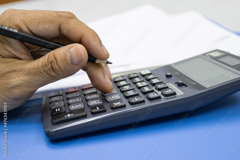 Hand of man use use calculators with documents of income, expenses, concept of life at work. Hand of man use use calculators with documents of income, expenses, concept of life at work.
