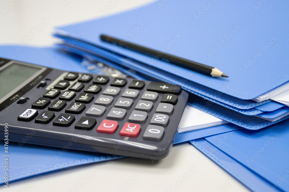 calculator with file folder on table in work office, concepts business and cost and financial planning selective focus calculator calculator with file folder on table in work office, concepts business and cost and financial planning selective focus calculator