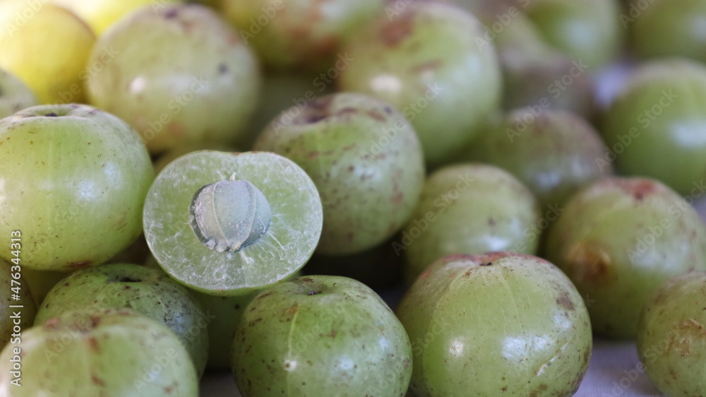 Fresh Indian gooseberry fruit. Close up Slice Amla or Amalaka (Phyllanthus emblica L.) is a round green forest fruit with natural mottled marks. selective focus