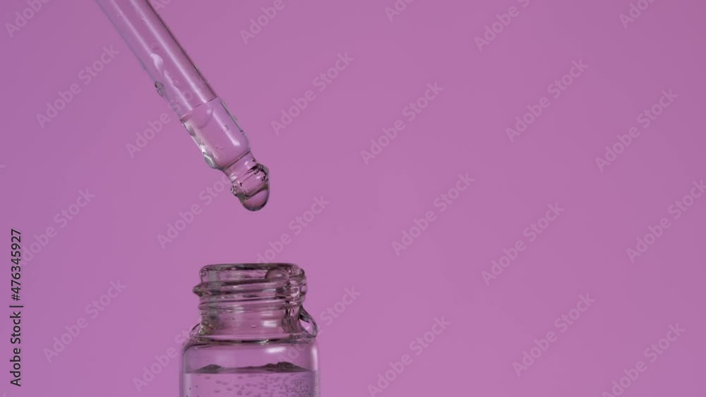 Drop of organic essence oil fall from pipette in glass bottle on violet background. Blend of essential oils. Aroma liquids, perfume. Natural remedies, aromatherapy. Organic bio alternative medicine Drop of organic essence oil fall from pipette in glass bottle on violet background. Blend of essential oils. Aroma liquids, perfume. Natural remedies, aromatherapy. Organic bio alternative medicine