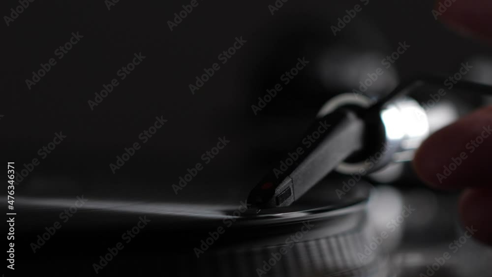 Male hand put needle on record spinning on turntable. Listening the music. Closeup Male hand put needle on record spinning on turntable. Listening the music. Closeup