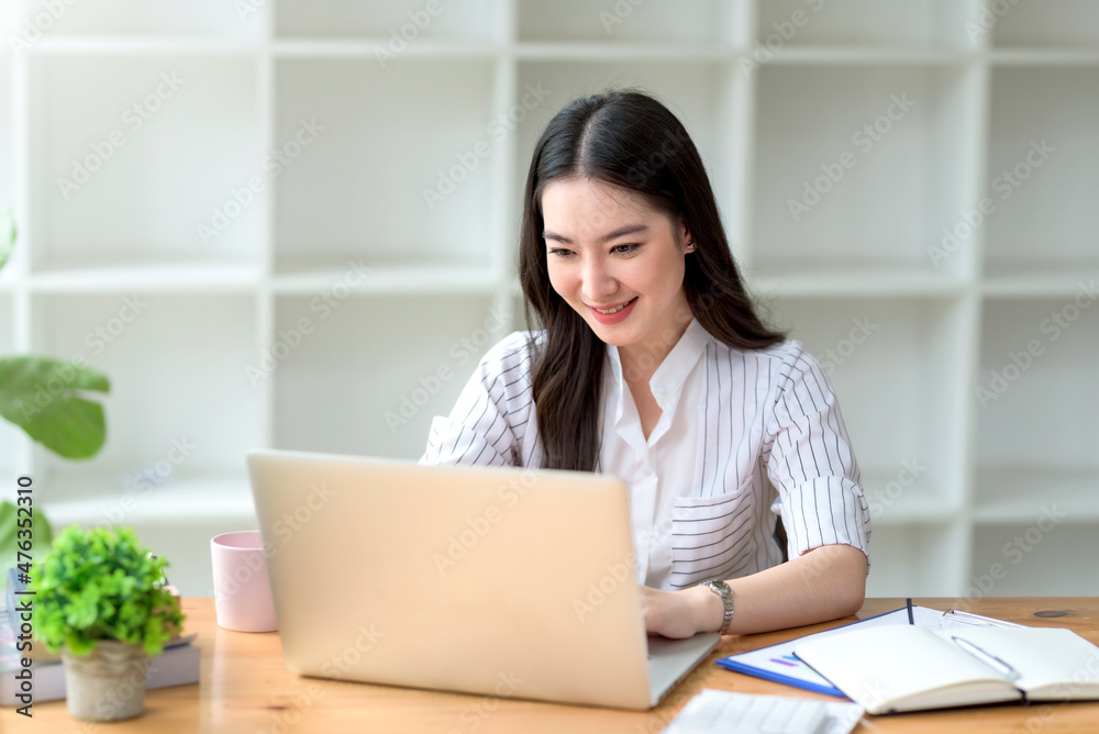 Portrait of smiling beautiful Asian businesswoman enjoy the idea sitting with laptop computer at office. Portrait of smiling beautiful Asian businesswoman enjoy the idea sitting with laptop computer at office.