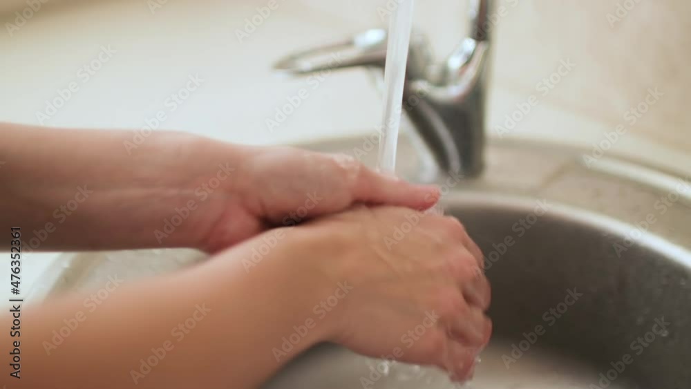 Washing and rinsing female hands in kitchen sink, close up Washing and rinsing female hands in kitchen sink, close up