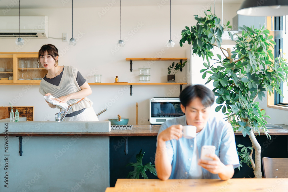 家事をしながら男性を見て怒る女性
