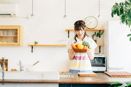 キッチンで野菜を持つ女性 