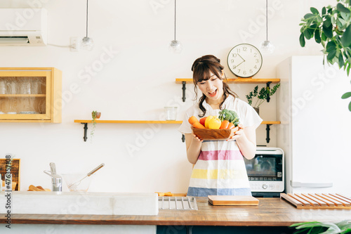 キッチンで野菜を持つ女性 