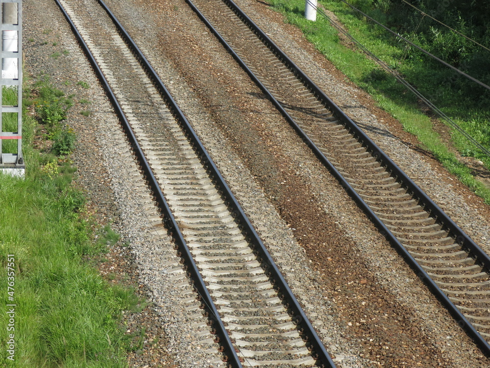 suburban railway tracks with poles and rails in summer