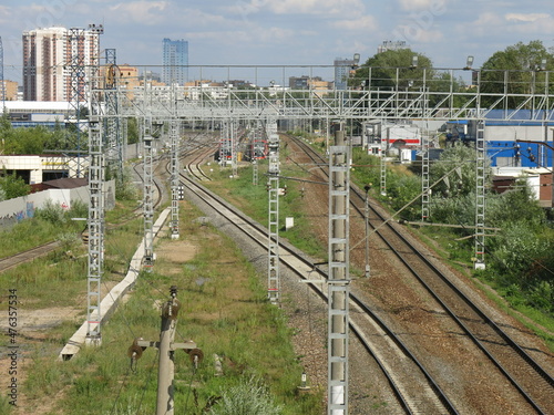 suburban railway tracks with poles and rails in summer