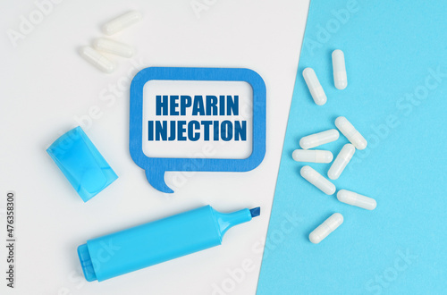 On a white and blue table are pills, a marker and a blue plaque with the inscription - Heparin Injection