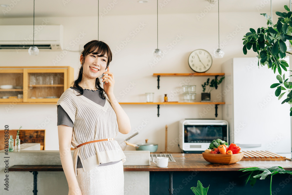 家でスマホを使う女性(通話・笑顔)
家でスマホを使う女性(通話・笑顔)