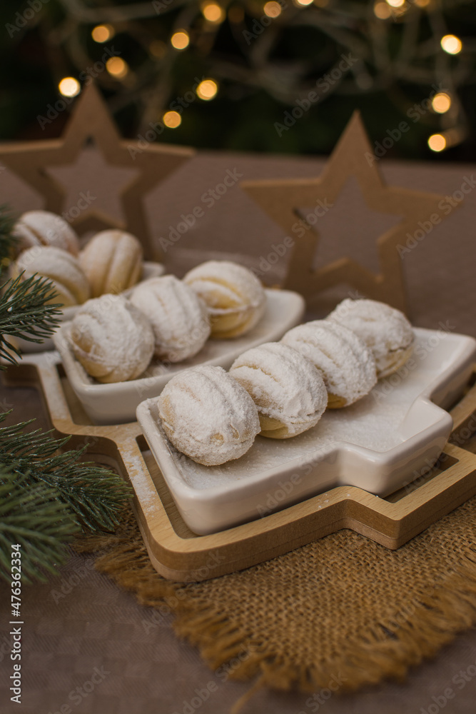 Nut-shaped cookies sprinkled with powdered sugar in a Christmas tree-shaped ceramic dish.