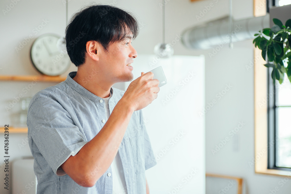 キッチンの前でホットドリンクを飲む男性
キッチンの前でホットドリンクを飲む男性