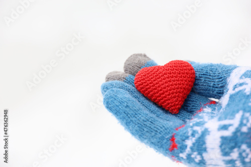 Red heart on palm of hand in warm knitted glove against the snow. Concept of a romantic love  Valentine s day or charity